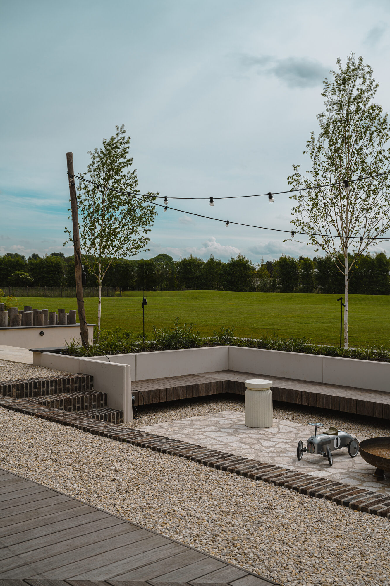 Verzonken zithoek in de tuin met een vloer van travertin flagstones en een vuurschaal